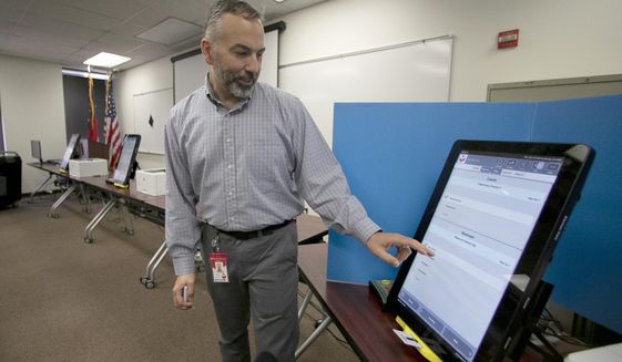 FILE- In this Sept. 16, 2019 file photo, Scott Tucker demonstrates the Dominion Voting system Georgia will use in Atlanta. Republican efforts to question the results of the 2020 election have led to two significant breaches of voting software that have alarmed election security experts who say they have increased the risk to elections in jurisdictions that use the equipment. (AP Photo/John Bazemore, File)