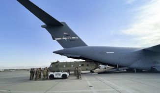 In this image provided by the Department of Defense, a CH-47 Chinook from the 82nd Combat Aviation Brigade, 82nd Airborne Division is loaded onto a U.S. Air Force C-17 Globemaster III at Hamid Karzai International Airport in Kabul, Afghanistan, Saturday, Aug, 28, 2021. (Department of Defense via AP)