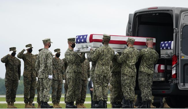 A carry team loads a transfer case with the remain of Navy Corpsman Maxton W. Soviak, 22, of Berlin Heights, Ohio, into a transfer vehicle during a casualty return at Dover Air Force Base, Del., Sunday, Aug. 29, 2021, for the 13 service members killed in the suicide bombing in Kabul, Afghanistan, on Aug. 26. (AP Photo/Carolyn Kaster)