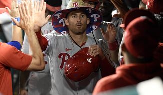 Philadelphia Phillies&#39; Brad Miller is congratulated in the dugout for his two-run home run against the Washington Nationals during the ninth inning of a baseball game Tuesday, Aug. 31, 2021, in Washington. The Phillies won 12-6. (AP Photo/Nick Wass)