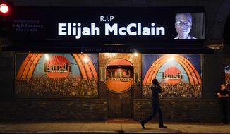 FILE - In this Aug. 24, 2020, file photo, a man walks past a display showing an image of Elijah McClain outside Laugh Factory during a candlelight vigil for McClain in Los Angeles.   Colorado’s attorney general plans to make an announcement Wednesday, Sept. 1, 2021 about the grand jury investigation into the death of McClain, a Black man who was put in a chokehold and injected with a powerful sedative two years ago in suburban Denver. (AP Photo/Jae C. Hong, File)
