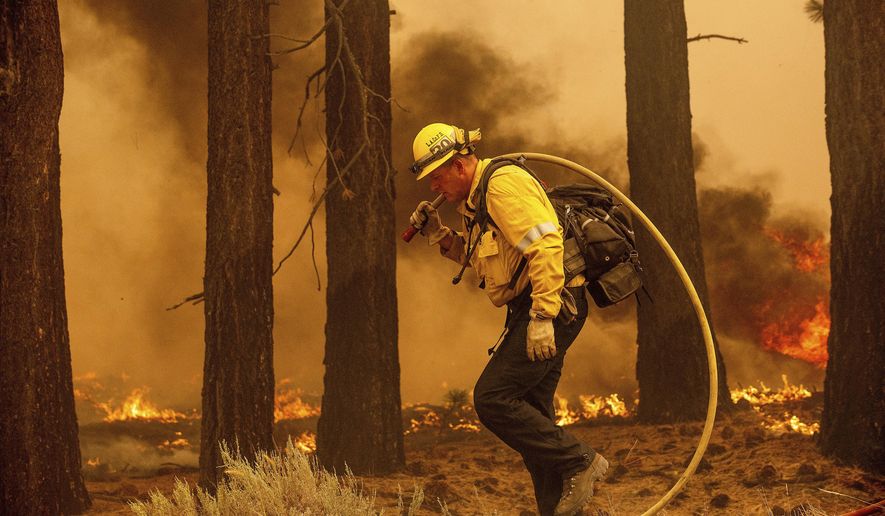A firefighter battles the Caldor Fire along Highway 89, Tuesday, Aug. 31, 2021, near South Lake Tahoe, Calif. (AP Photo/Noah Berger)