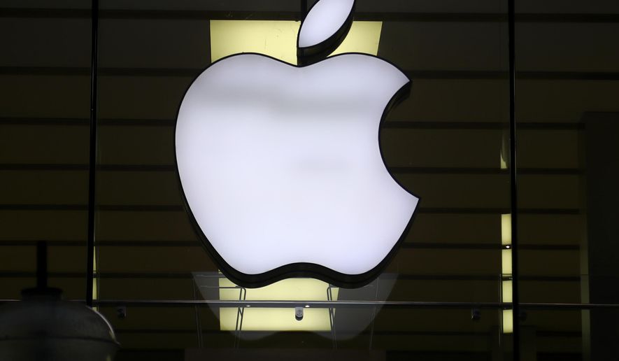 In this Wednesday, Dec. 16, 2020 file photo, the logo of Apple is illuminated at a store in the city center in Munich, Germany. U.S. tech giant Apple Inc. cut a deal with Chinese officials to protect its business lines in the country, working with government regulators on rules that would allow the company to operate more freely in the country while supporting key government priorities, according to a published report. (AP Photo/Matthias Schrader, File)