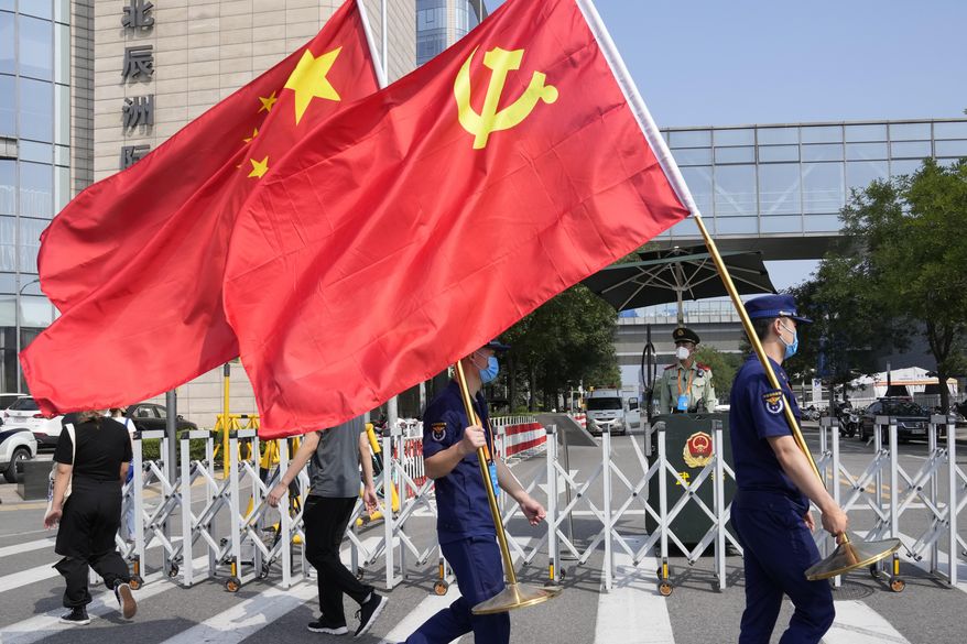 Security personnel holding the Communist Party and Chinese national flags prepare to enter the venue for the China International Fair for Trade in Services (CIFTIS) in Beijing on China, Thursday, Sept. 2, 2021. (AP Photo/Ng Han Guan)