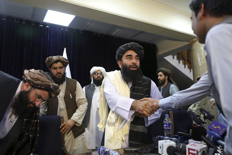 In this Aug. 17, 2021, photo, Taliban spokesman Zabihullah Mujahid, shakes hands with a journalist after his first news conference, in Kabul, Afghanistan. Mujahid vowed that the Taliban would respect women's rights, forgive those who resisted them and ensure a secure Afghanistan as part of a publicity blitz aimed at convincing world powers and a fearful population that they have changed. (AP Photo/Rahmat Gul) **FILE**