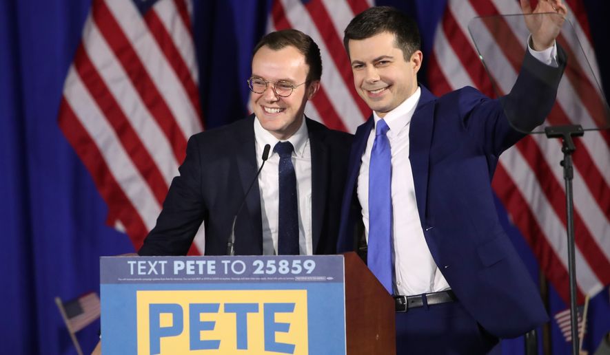 In this Feb. 11, 2020, file photo Democratic presidential candidate former South Bend, Ind., Mayor Pete Buttigieg acknowledges supported as he stands on stage with his husband Chasten Buttigieg at a primary night election rally in Nashua, N.H. Transportation Secretary Pete Buttigieg has announced that he and husband Chasten have become parents. Buttigieg, the first openly gay Cabinet secretary confirmed by the Senate, posted a photo of their two children on Saturday, Sept. 4, 2021, on his personal Twitter account. (AP Photo/Mary Altaffer, File)