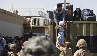 In this Aug. 26, 2021, image provided by the U.S. Army, an Afghan man hands his child to a British Paratrooper assigned to 2nd Battalion, Parachute Regiment while a member of 1st Brigade Combat Team, 82nd Airborne Division conducts security at Hamid Karzai International Airport in Kabul, Afghanistan. (U.S. Army via AP) **FILE**