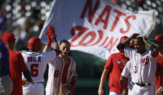 Washington Nationals&#39; Carter Kieboom (8) high-fives Alex Avila (6) after hitting a walkoff single to drive in Josh Bell during the ninth inning of a baseball game against the New York Mets, Monday, Sept. 6, 2021, in Washington. Nationals&#39; Alcides Escobar, right, looks on. (AP Photo/Nick Wass)