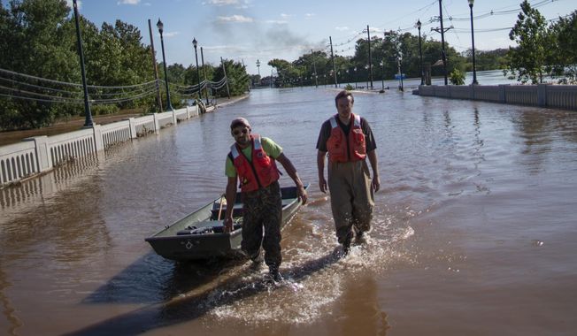 United States Geological Survey workers push a boat as they look for residents on a street flooded as a result of the remnants of Hurricane Ida in Somerville, NJ., Thursday, Sept. 2, 2021. (AP Photo/Eduardo Munoz Alvarez)