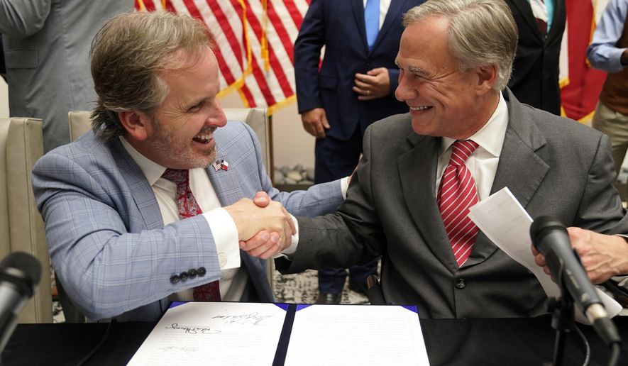 Texas Gov. Greg Abbott (right) and state Sen. Bryan Hughes, R-Mineola, shake hands after Abbott signed Senate Bill 1, also known as the election integrity bill, into law in Tyler, Texas, Tuesday, Sept. 7, 2021. The sweeping bill signed Tuesday by the two-term Republican governor further tightens Texas’ strict voting laws. (AP Photo/LM Otero) **FILE**