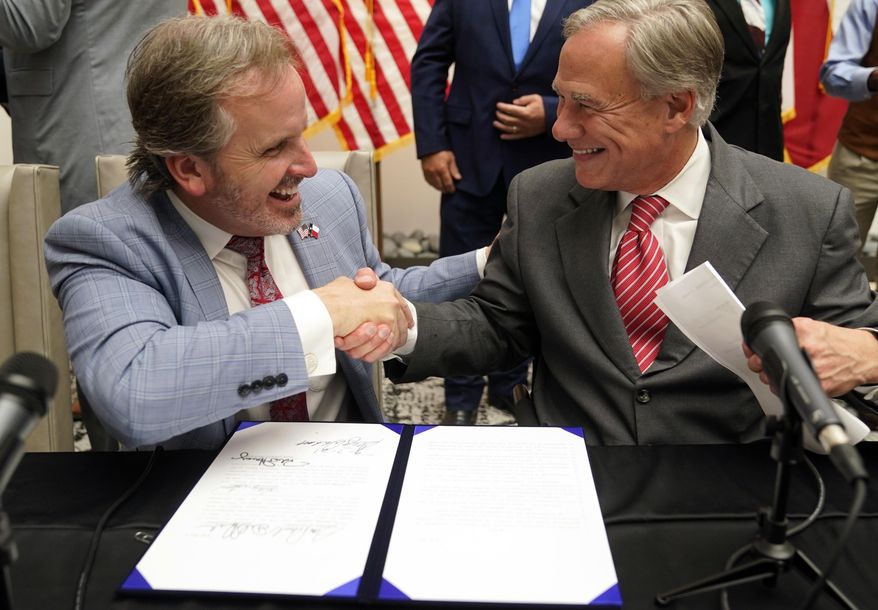 Texas Gov. Greg Abbott (right) and state Sen. Bryan Hughes, R-Mineola, shake hands after Abbott signed Senate Bill 1, also known as the election integrity bill, into law in Tyler, Texas, Tuesday, Sept. 7, 2021. The sweeping bill signed Tuesday by the two-term Republican governor further tightens Texas’ strict voting laws. (AP Photo/LM Otero) **FILE**