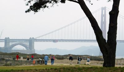 People walk through Crissy Field with the Golden Gate Bridge in the background in San Francisco, Friday, Sept. 26, 2003. When the Army decided to transfer the Presidio base in a coveted corner of San Francisco to the National Park Service in the early-1990s, there was much caterwauling from environmentalists about the future of the jewel at the foot of the Golden Gate Bridge.(AP Photo/Eric Risberg)