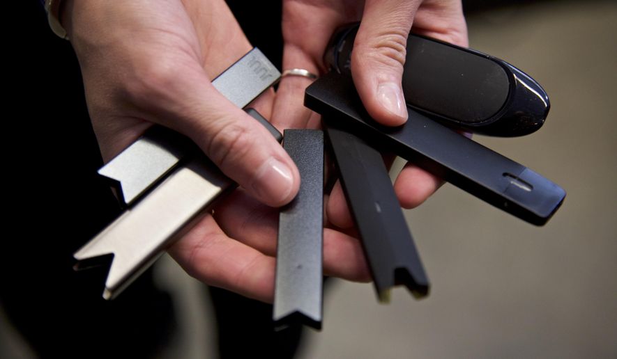 In this April 16, 2019, photo, a researcher holds vape pens in a laboratory in Portland, Ore. On Thursday, Sept. 9, 2021, U.S. health officials delayed a high-stakes decision on whether to permit best-selling vaping brand Juul to stay on the market, while ordering thousands of other electronic cigarettes off store shelves. (AP Photo/Craig Mitchelldyer) **FILE**