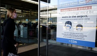 In this July 2, 2021 photo, a traveler walks in Terminal 3 as a sign stating face coverings are required is displayed at O&#39;Hare International Airport in Chicago.  The leading U.S. airlines say that the rise in COVID-19 cases is hurting ticket sales and pushing back the recovery of the travel industry. American, United, Delta, Southwest and others reported setbacks in regulatory filings Thursday, Sept. 9. (AP Photo/Nam Y. Huh) **FILE**