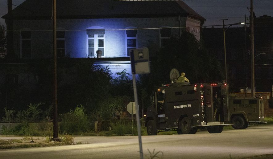 Illinois State Police in armored trucks shine a spotlight on a building near St. Louis Avenue and Sixth Street in East St. Louis, Ill. during a manhunt after a shooting on Thursday, Sept. 9, 2021. Multiple victims were reported shot in southern Illinois late Thursday afternoon and  at least three suspects who crashed their getaway vehicle into a passenger train remained on the loose, authorities said. (Daniel Shular/St. Louis Post-Dispatch via AP)