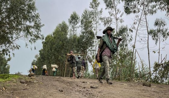 An unidentified armed militia fighter walks down a path as villagers flee with their belongings in the other direction, near the village of Chenna Teklehaymanot, in the Amhara region of northern Ethiopia Thursday, Sept. 9, 2021. At the scene of one of the deadliest battles of Ethiopia&#39;s 10-month Tigray conflict, witness accounts reflected the blurring line between combatant and civilian after the federal government urged all capable citizens to stop Tigray forces &amp;quot;once and for all.&amp;quot; (AP Photo)