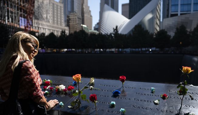 Mourners gather at the north pool adorned with flowers during ceremonies to commemorate the 20th anniversary of the Sept. 11, 2001 terrorist attacks, Saturday, Sept. 11, 2021, at the National September 11 Memorial &amp; Museum in New York. (AP Photo/John Minchillo)