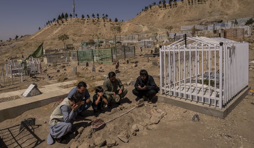 FILE - In this Monday, Sept. 13, 2021 file photo, the Ahmadi family pray at the cemetery next to family graves of family members killed by a US drone strike, in Kabul, Afghanistan. Zemerai Ahmadi an Afghan man who was killed in a U.S. drone strike last month was an enthusiastic and beloved longtime employee at an American humanitarian organization, his colleagues say, painting a stark contrast to the Pentagon’s claims that he was an Islamic State group militant about to carry out an attack on American troops. (AP Photo/Bernat Armangue)