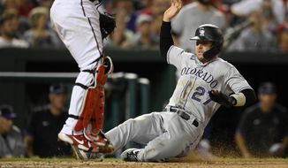 Colorado Rockies&#39; Trevor Story (27) slides home to score on a single by Ryan McMahon during the sixth inning of a baseball game against the Washington Nationals, Friday, Sept. 17, 2021, in Washington. (AP Photo/Nick Wass)