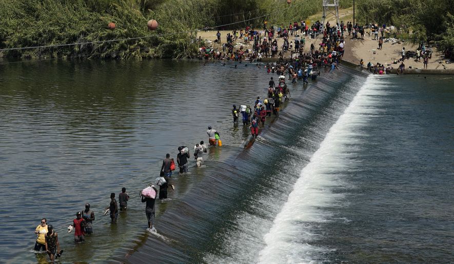 Haitian migrants use a dam to cross into the United States from Mexico, Saturday, Sept. 18, 2021, in Del Rio, Texas. The U.S. plans to speed up its efforts to expel Haitian migrants on flights to their Caribbean homeland, officials said Saturday as agents poured into the Texas border city where thousands of Haitians have gathered after suddenly crossing into the U.S. from Mexico. (AP Photo/Eric Gay)