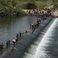 Haitian migrants use a dam to cross into the United States from Mexico, Saturday, Sept. 18, 2021, in Del Rio, Texas. The U.S. plans to speed up its efforts to expel Haitian migrants on flights to their Caribbean homeland, officials said Saturday as agents poured into the Texas border city where thousands of Haitians have gathered after suddenly crossing into the U.S. from Mexico. (AP Photo/Eric Gay)
