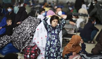 A girl from Afghanistan waits with other evacuees to fly to the United States or an other save location in a makeshift departure gate inside a hanger at the United States Air Base in Ramstein, Germany, Wednesday, Sept. 1, 2021. One of largest American military community overseas gets to a transport hub and houses thousands Afghan evacuees. (AP Photo/Markus Schreiber)