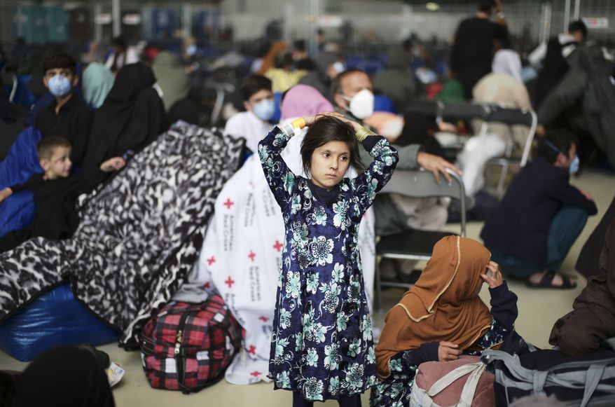 A girl from Afghanistan waits with other evacuees to fly to the United States or an other save location in a makeshift departure gate inside a hanger at the United States Air Base in Ramstein, Germany, Wednesday, Sept. 1, 2021. One of largest American military community overseas gets to a transport hub and houses thousands Afghan evacuees. (AP Photo/Markus Schreiber)