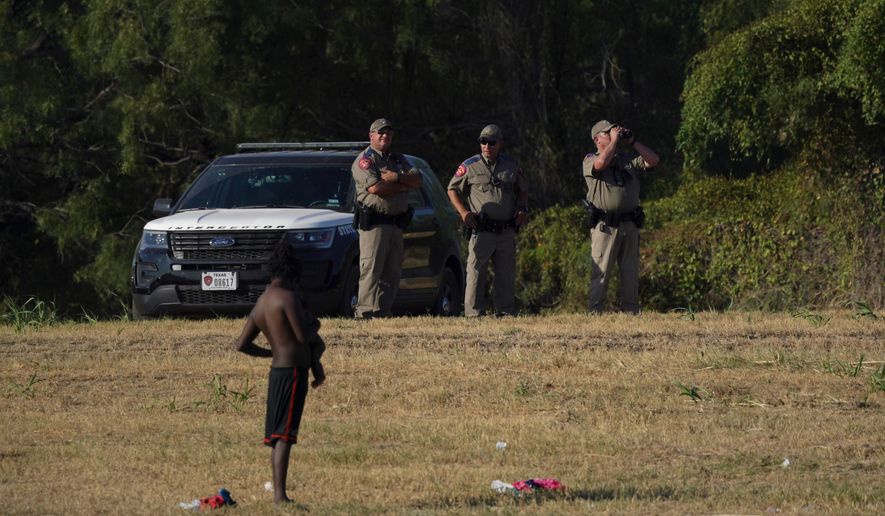 Texas Department of Public Safety Highway Patrol officers watch as migrants, many from Haiti, wade across the Rio Grande from Del Rio, Texas, to return to Ciudad Acuna, Mexico, Tuesday, Sept. 21, 2021, to avoid deportation from the U.S.  The U.S. is flying Haitians camped in a Texas border town back to their homeland and blocking others from crossing the border from Mexico. (AP Photo/Fernando Llano)