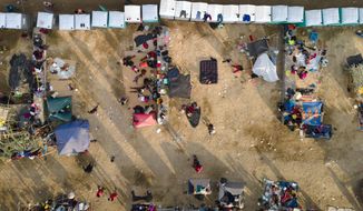 Migrants, many from Haiti, are seen at an encampment along the Del Rio International Bridge near the Rio Grande, Tuesday, Sept. 21, 2021, in Del Rio, Texas. The U.S. is flying Haitians camped in a Texas border town back to their homeland and blocking others from crossing the border from Mexico. (AP Photo/Julio Cortez)