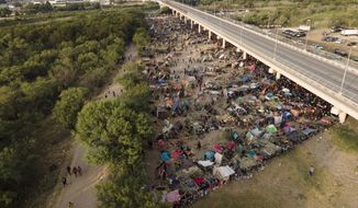 Migrants, many from Haiti, are seen at an encampment along the Del Rio International Bridge near the Rio Grande, Tuesday, Sept. 21, 2021, in Del Rio, Texas.  The options remaining for thousands of Haitian migrants straddling the Mexico-Texas border are narrowing as the United States government ramps up to an expected six expulsion flights to Haiti and Mexico began busing some away from the border.  (AP Photo/Julio Cortez)