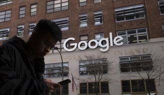 In this file photo dated Monday, Dec. 17, 2018, a man using a mobile phone walks past Google offices in New York. Google is planning to buy New York&#39;s St.  John’s Terminal for $2.1 billion, making it the anchor of its Hudson Square campus. Alphabet and Google Chief Financial Officer Ruth Porat said Tuesday, Sept. 21, 2021,  that the company is looking to invest more than $250 million in its New York campus this year. (AP Photo/Mark Lennihan)  **FILE**