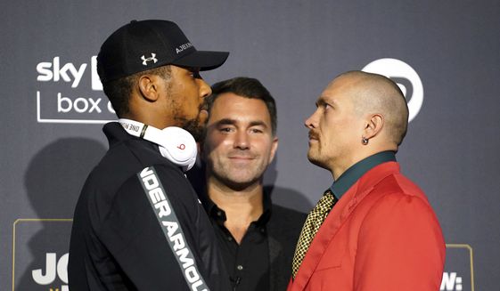 British boxer Anthony Joshua, left,  poses for a photo with Ukrainian boxer Oleksandr Usyk, right, with Chairman of Matchroom Boxing Eddie Hearn at centre, during a press conference at the Tottenham Hotspur Stadium, in London, Thursday, Sept. 23, 2021. Joshua faces Oleksandr Usyk in the second defense of his second spell as world heavyweight champion. Joshua holds the IBF, WBA and WBO belts and had been hoping to fight WBC champion Tyson Fury in an effort to become the undisputed heavyweight champ. Fury has to fight Deontay Wilder instead so Usyk is a replacement. (Zac Goodwin/PA via AP)