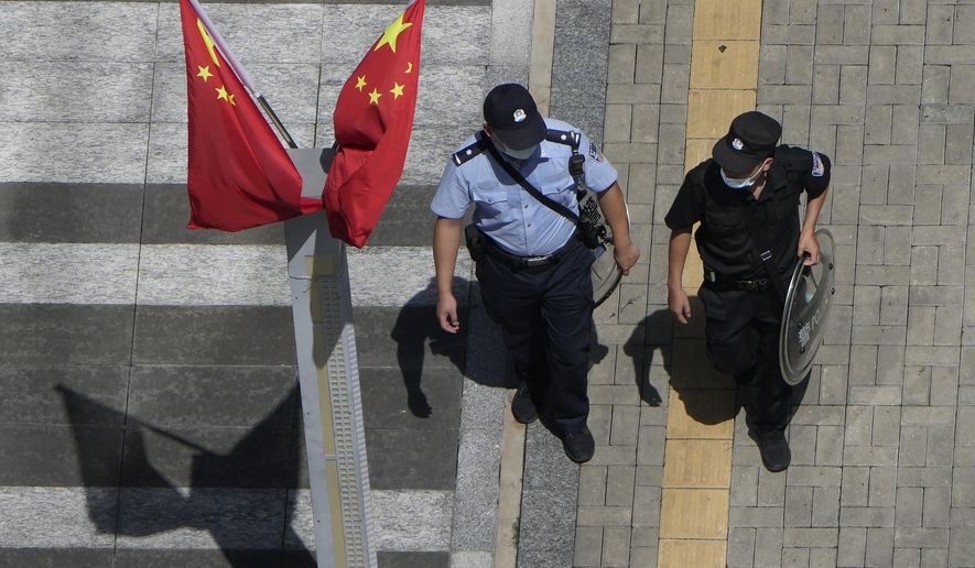 A policeman, right, and security guard walk past Chinese flags outside the Evergrande headquarters in Shenzhen, China, Friday, Sept. 24, 2021. (AP Photo/Ng Han Guan)