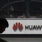 In this Thursday, May 16, 2019 file photo, a man is silhouetted near the Huawei logo in Beijing. Lithuanian cybersecurity authorities are urging the country’s governmental agencies to abandon the use of Chinese smartphone brands. Lithuania’s National Cyber Security Center said Tuesday, Sept. 21, 2021 it found four major cybersecurity risks for devices made by Huawei and Xiaomi. (AP Photo/Ng Han Guan, file)