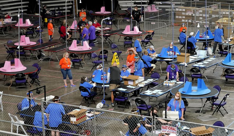 In this May 6, 2021, file photo, Maricopa County ballots cast in the 2020 general election are examined and recounted by contractors working for Florida-based company, Cyber Ninjas, at Veterans Memorial Coliseum in Phoenix. (AP Photo/Matt York, Pool) ** FILE **