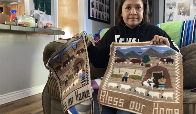 Seraphine Warren poses for a photo in her home in Tooele, Utah, on Sept. 23, 2021, with a rug made by her aunt, Navajo rug weaver Ella Mae Begay. Begay, 62, disappeared in June, one of thousands of missing Indigenous women across the U.S. The extensive coverage of the Gabby Petito case is renewing calls to also shine a spotlight on missing people of color. (AP Photo/Lindsay Whitehurst)