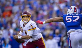 Washington Football Team quarterback Taylor Heinicke (4) flees the pass rush of Buffalo Bills defensive end A.J. Epenesa (57) during the second quarter of an NFL football game, Sunday, Sept. 26, 2021, in Orchard Park, N.Y. (AP Photo/Brett Carlsen)