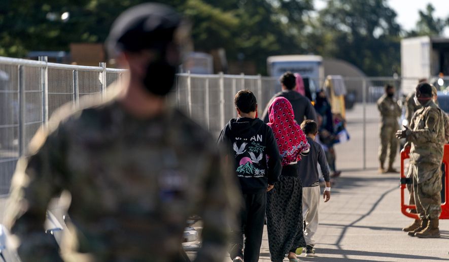 Afghan refugees walk through an Afghan refugee camp at Joint Base McGuire Dix Lakehurst, N.J., Monday, Sept. 27, 2021. The camp currently holds approximately 9,400 Afghan refugees and has a capacity to hold up to 13,000. (AP Photo/Andrew Harnik)