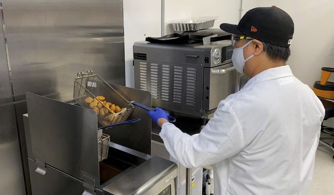 Nathan Foot, R&amp;amp;D chef at Impossible Foods, takes its new meatless nuggets out of a deep fryer in the company’s test kitchen on Sept. 21, 2021, in Redwood City, Calif. The plant-based nuggets taste are designed to taste like chicken. (AP Photo/Terry Chea)