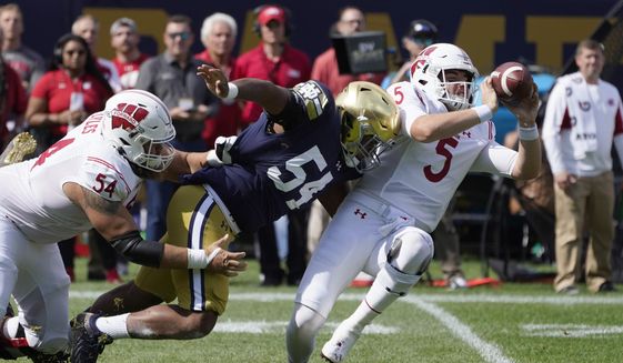 Wisconsin quarterback Graham Mertz (5) makes a two-handed pass to avoid the pressure from Notre Dame defensive lineman Jacob Lacey after Lacey got past lineman Kayden Lyles during the first half of an NCAA college football game Saturday, Sept. 25, 2021, in Chicago. (AP Photo/Charles Rex Arbogast) **FILE**