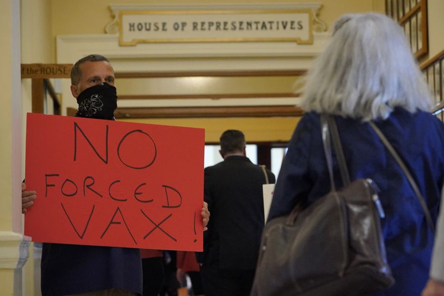A protester against mandated vaccines for healthcare workers holds sign as legislators arrive for a special session at the State House, Wednesday, Sept. 29, 2021, in Augusta, Maine. (AP Photo/Robert F. Bukaty) **FILE**