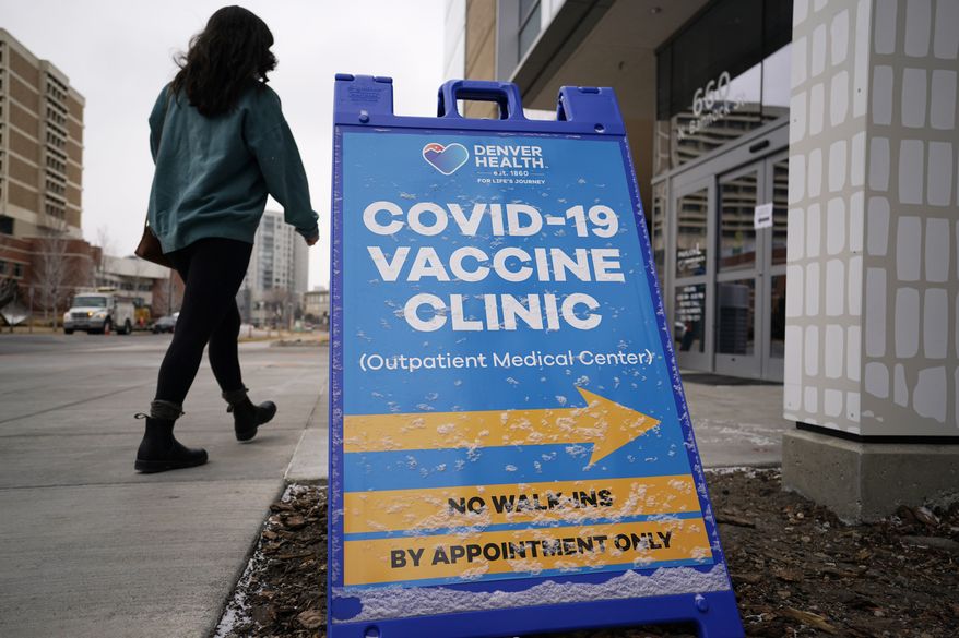 In this Feb. 13, 2021, photo, a woman heads in for a COVID-19 vaccination during a mass vaccination of 1,000 employees of Denver Public Schools including teachers, administrators, custodial workers and bus drivers at Denver Health, in Denver. A judge on Wednesday, Sept. 29, 2021, dismissed an attempt by a group of Denver police officers to block the city's vaccine mandate from taking effect. (AP Photo/David Zalubowski) **FILE**