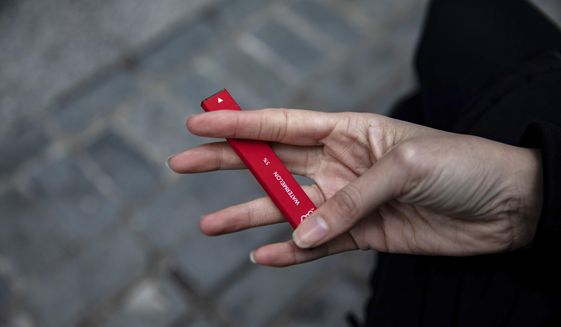 In this Jan. 31, 2020, file photo a woman holds a Puff Bar flavored disposable vape device in New York.  Government researchers reported a big drop in teen vaping this year as many U.S. students were forced to learn from home due to the COVID-19 pandemic. U.S. health officials urged caution in interpreting the numbers Thursday, Sept. 30, 2021, which were collected using an online questionnaire for the first time.(AP Photo/Marshall Ritzel)