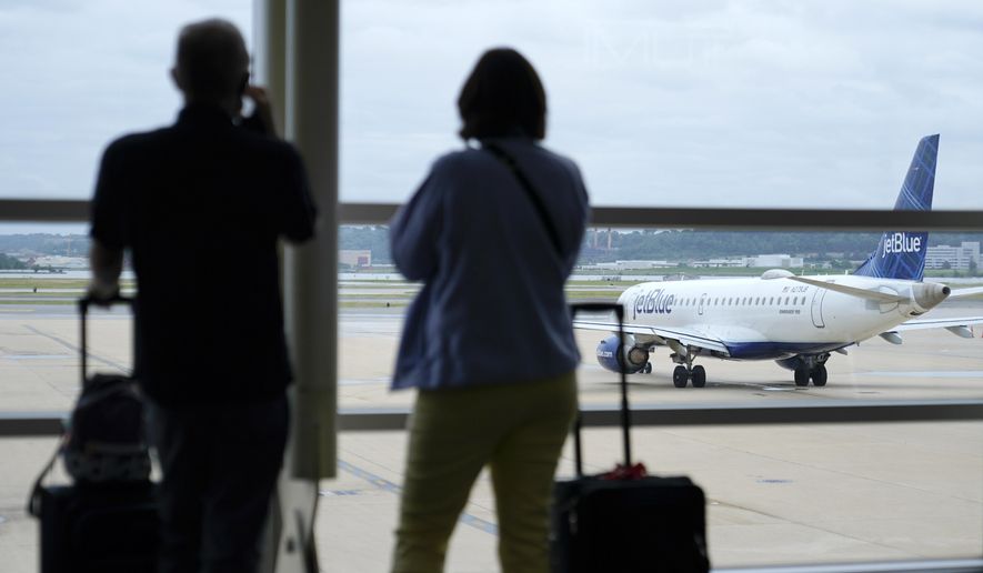In this Tuesday, May 25, 2021, file photo, travelers watch a JetBlue Airways aircraft taxi away from a gate at Ronald Reagan Washington National Airport in Arlington, Va. (AP Photo/Patrick Semansky, File)