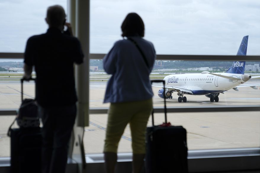 In this Tuesday, May 25, 2021, file photo, travelers watch a JetBlue Airways aircraft taxi away from a gate at Ronald Reagan Washington National Airport in Arlington, Va. (AP Photo/Patrick Semansky, File)