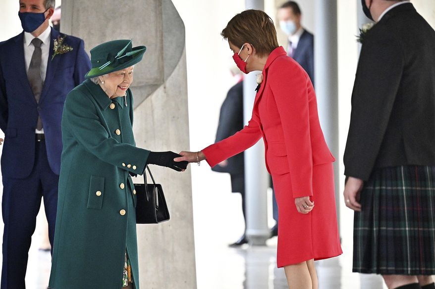 Britain&#39;s Queen Elizabeth II is greeted by Scotland&#39;s First Minister Nicola Sturgeon, right, as she arrives at the Scottish Parliament to deliver a speech in the debating chamber to mark the official start of the sixth session of Parliament, in Edinburgh, Scotland, Saturday Oct. 2, 2021. (Jeff J Mitchell/PA via AP)