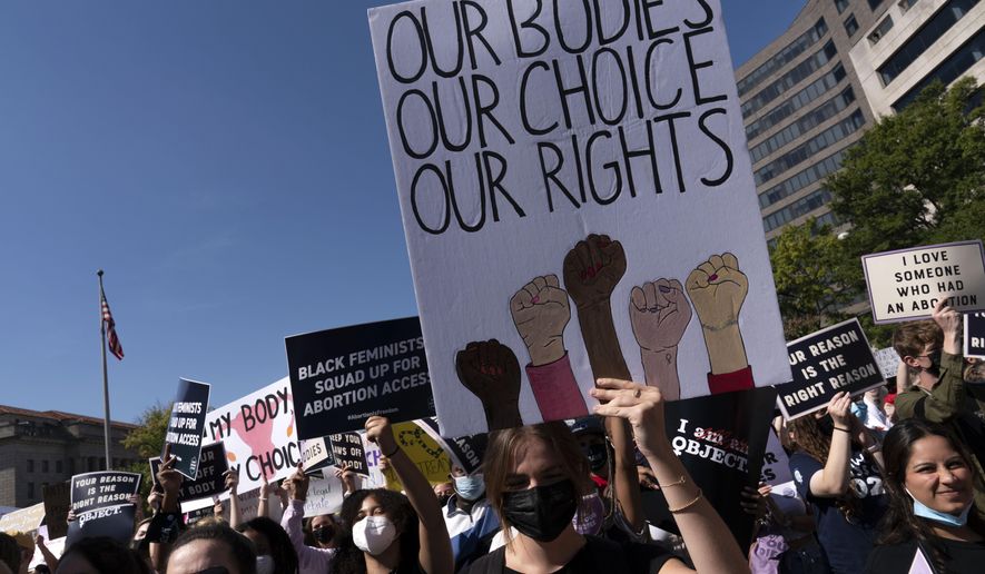 Activists hold signs during the Women&#39;s March rally at Freedom Plaza, in Washington, Saturday, Oct. 2, 2021. (AP Photo/Jose Luis Magana)