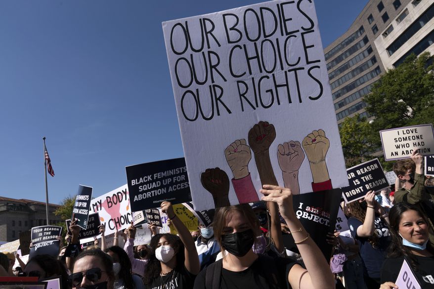 Activists hold signs during the Women's March rally at Freedom Plaza, in Washington, Saturday, Oct. 2, 2021. (AP Photo/Jose Luis Magana)