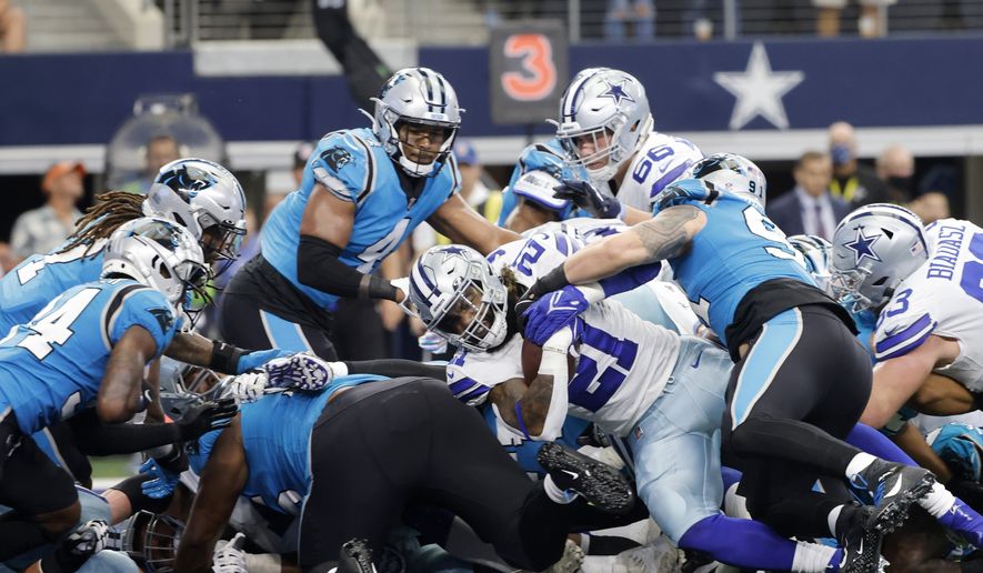 Dallas Cowboys running back Ezekiel Elliott (21) escapes the grasp of Carolina Panthers defensive end Morgan Fox, right, to score a touchdown on a running play in the first half of a NFL football game in Arlington, Texas, Sunday, Oct. 3, 2021. (AP Photo/Michael Ainsworth)