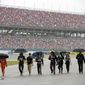 Team members walk through pit row in the rain before a NASCAR Cup series auto race Sunday, Oct. 3, 2021, in Talladega, Ala. (AP Photo/John Amis)